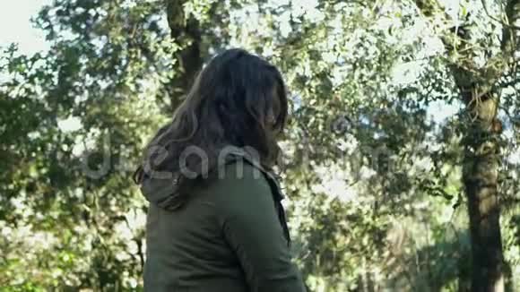 坐在森林里的年轻女子在她的耳朵后面摘头发视频的预览图