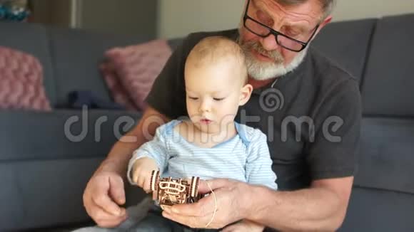 爷爷和孙子正在玩木玩具在家里一起休息时拥抱和微笑快乐爷爷视频的预览图