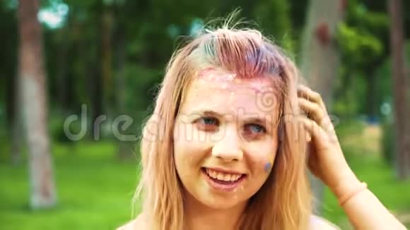 一位年轻女子的肖像金发上带着五颜六色的粉末对着镜头微笑视频的预览图