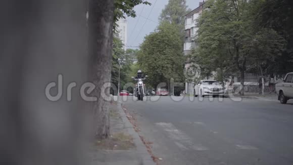 男人或女人穿着摩托车装备骑摩托车沿着城市道路休闲自行车视频的预览图
