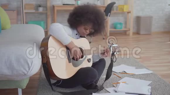 非洲裔美国妇女有非洲发型作曲弹吉他坐在地上视频的预览图