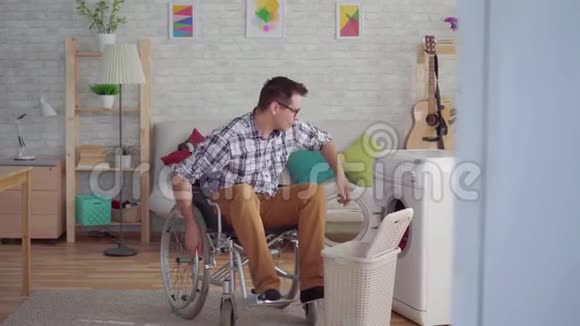 一个坐轮椅的中年男子做家务用洗衣机视频的预览图