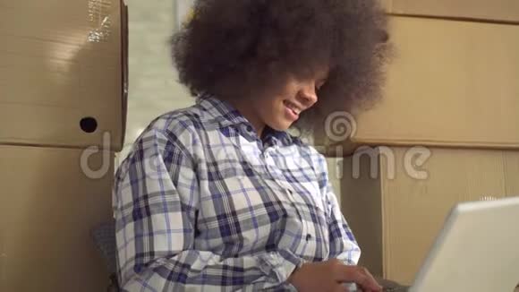 把非洲女人的发型贴在地板上用笔记本电脑视频的预览图