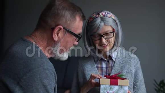 成熟的夫妻在圣诞节晚上在家男人送妻子礼物精美的圣诞装饰盒视频的预览图