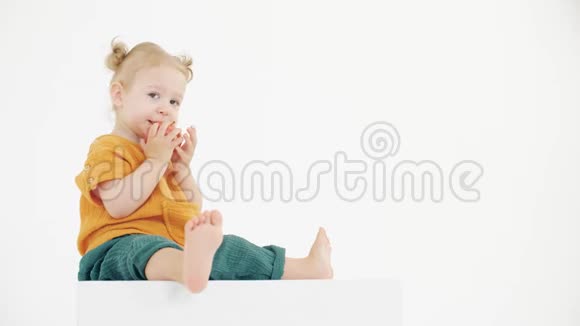 穿着橙色和绿色衣服在白色背景下吃苹果的攻击性婴儿视频的预览图