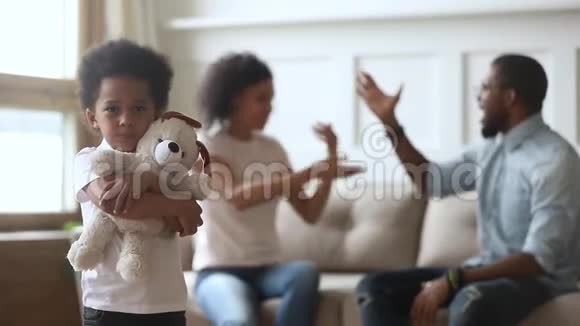 父母吵架时不快乐的小非洲儿子拥抱玩具视频的预览图