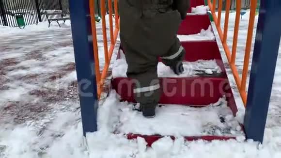 一个穿着冬季连衣裙的小孩子爬上楼梯孩子们在冬天滑倒视频的预览图