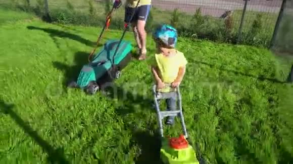 快乐活泼的幼儿男孩爸爸面前有玩具割草机万向节运动视频的预览图