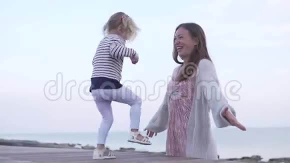 妈妈和女儿在海边的水边玩耍视频的预览图