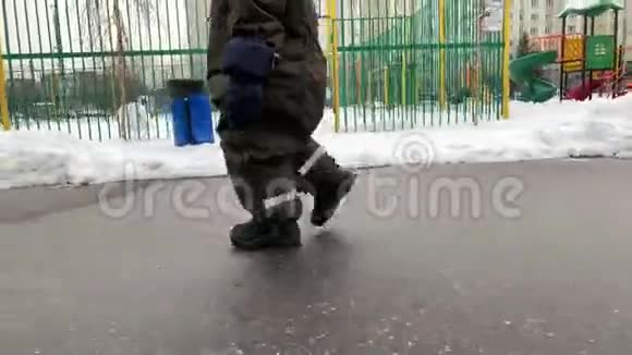 一个小孩子的脚在冬天的雪和柏油路上迈出我的第一步小宝宝学会走路第一批视频的预览图
