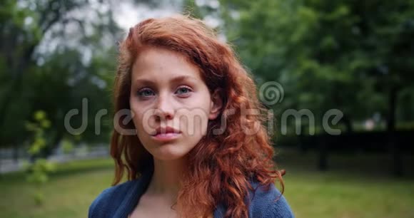 公园里站着一位红头发的严肃女士的慢镜头画像视频的预览图