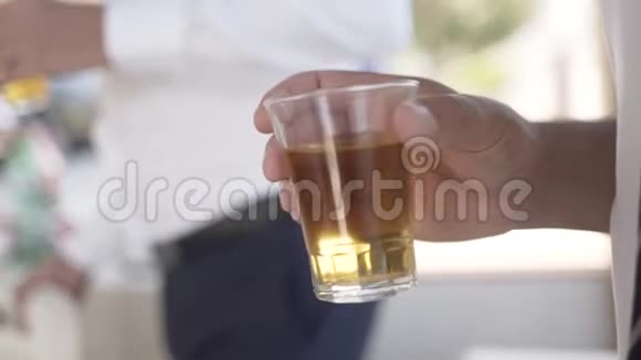 在模糊的背景上特写男人拿着一杯酒精行动老人手里拿着一杯白兰地视频的预览图