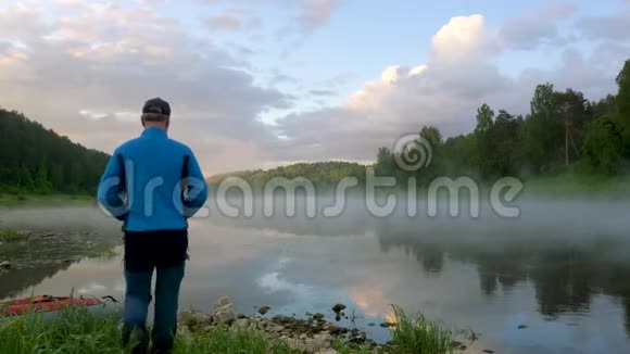 人站在宁静的河岸蓝天下有雾视频的预览图