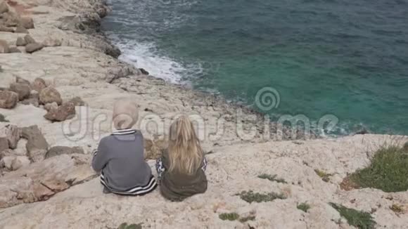 一个男孩和一个小女孩正坐在悬崖边看着视频的预览图