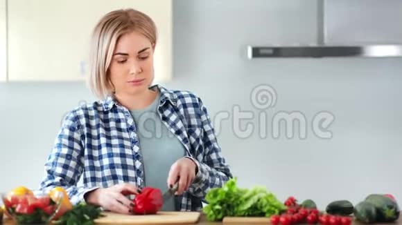 自信的年轻女子用刀中特写在木板上切鲜红甜椒视频的预览图