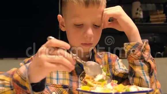 小男孩正在吃甜点在白色盘子里放着冰淇淋饼干和水果视频的预览图