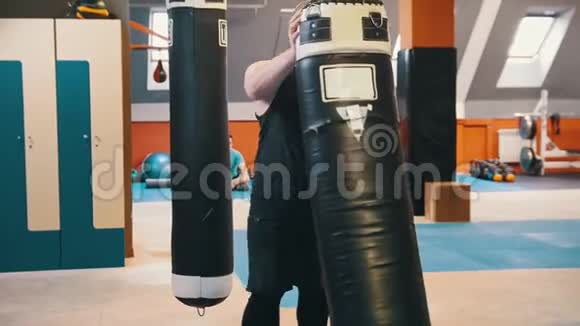 一个健美男子举起和扛在肩膀上的拳击袋在健身房视频的预览图