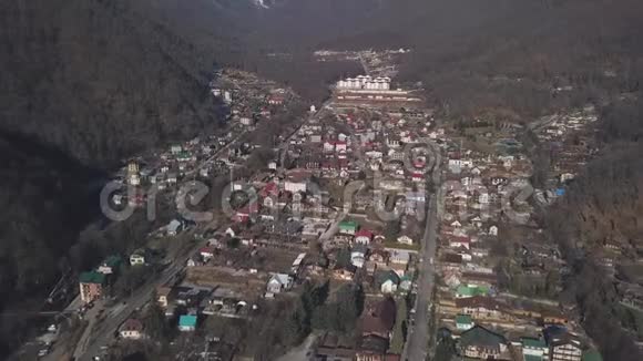 鸟瞰冬季奥地利村在山谷附近风景如画的阳光阿尔普山剪辑在路上飞过视频的预览图