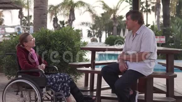 一位坐轮椅的老妇人正在旅馆里和丈夫谈话视频的预览图