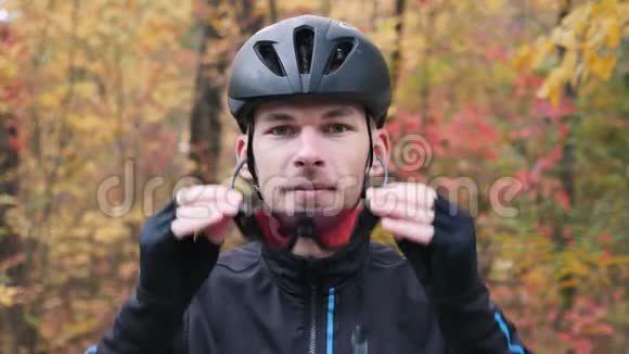 在秋季公园内培育专业三项运动员年轻迷人的男性自行车手准备训练戴上运动眼镜视频的预览图