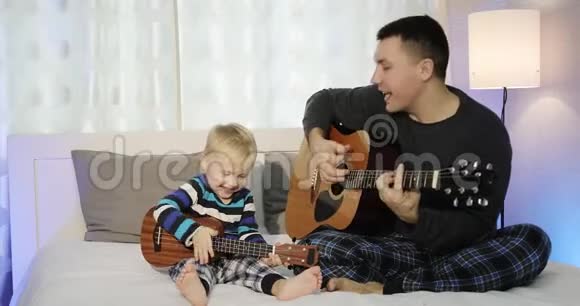 爸爸和儿子坐在床上弹吉他视频的预览图