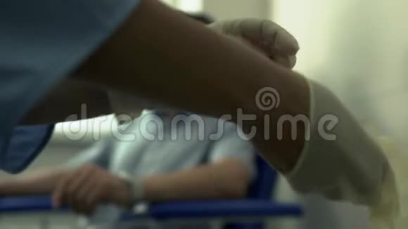 护士双手模糊戴上手套准备给坐在上面的英俊的成年病人抽血视频的预览图