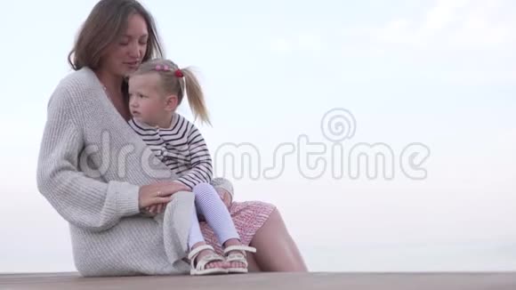 妈妈抱着小女儿妈妈和女儿在海滩上看日落视频的预览图