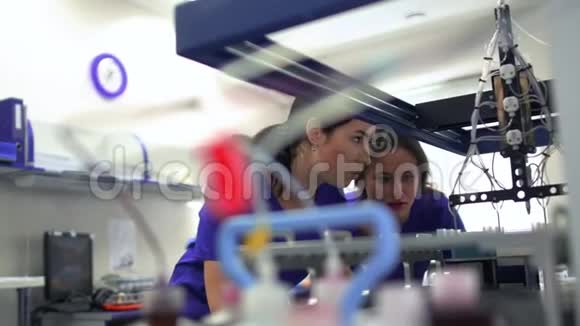描绘了两名穿蓝色制服的年轻妇女和控制实验室药物制造的橡胶手套开展活动视频的预览图