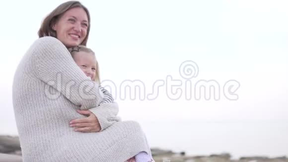 妈妈在海边的木板路上拥抱她的小女儿视频的预览图