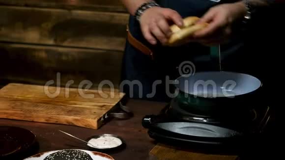 把男厨师的手拿着汉堡包放在一个木板上周围是不同的炊具和视频的预览图