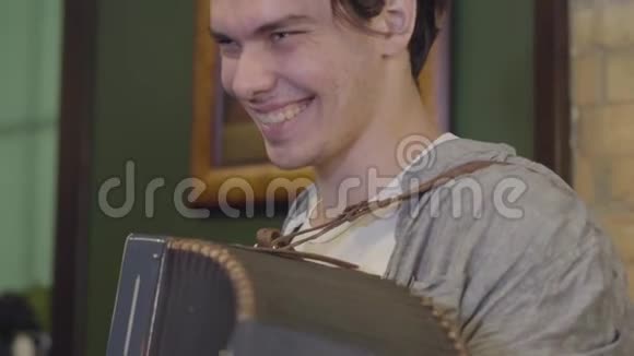 弹手风琴的熟练青年微笑着旧乐器上欢快的音乐民间观念视频的预览图