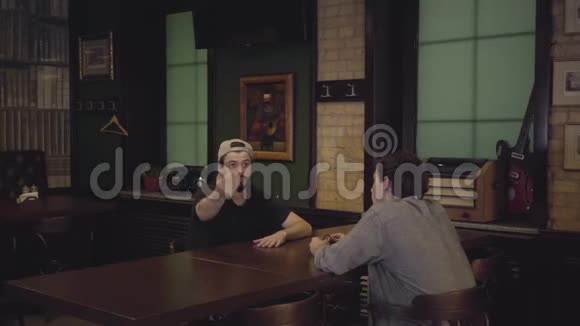 一个梳着辫子的女服务员穿着白色衬衫和紧身胸衣给坐在酒吧桌子旁的男人带来了冰镇啤酒视频的预览图