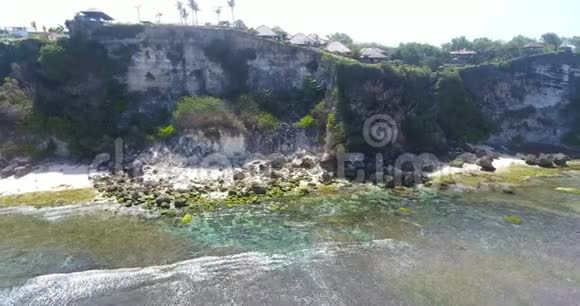 岩石海岸线的无人机镜头美丽的海洋与飞溅的波浪上午在印尼巴厘岛巴厘岛热带海滩视频的预览图