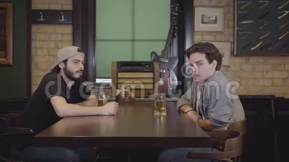 两个男人坐在酒吧里一起喝啤酒一个身材漂亮的女孩走过桌子一个男人在照顾她视频的预览图