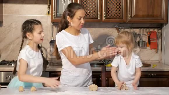 顽皮的妈妈和两个女儿在厨房一起做饭互相抹面粉一起玩得开心视频的预览图