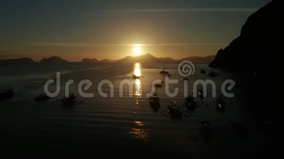 日落于大海和岛屿菲律宾巴拉望日落时带船的海湾空中无人机视频的预览图