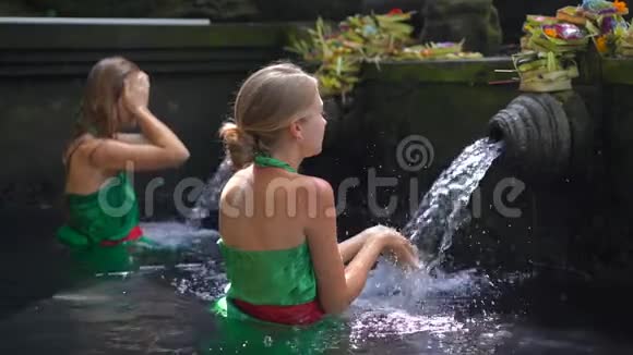 两名年轻女子在印度尼西亚的冬青泉参观时的慢镜头蒂塔恩普尔圣水泉在巴厘岛视频的预览图