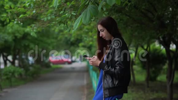 斯洛莫春天坐在户外用手机上网的漂亮女孩视频的预览图