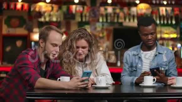 一群朋友在酒吧喝咖啡边看智能手机屏幕边讨论视频的预览图