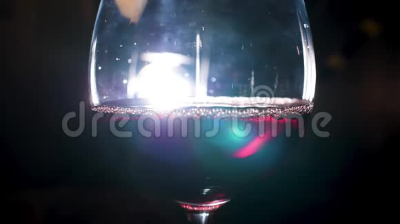 创意点亮的一杯起泡葡萄酒在黑色背景上有装饰效果库存录像靠近红色闪闪发光视频的预览图