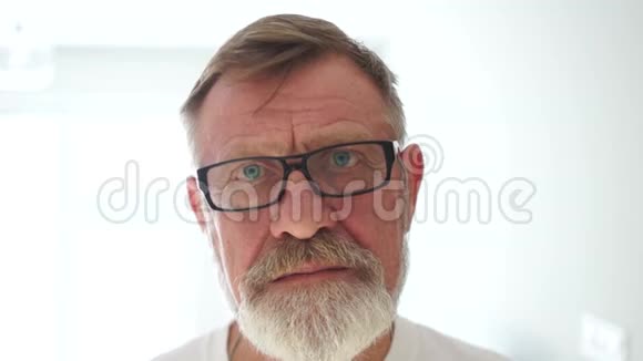 白色背景上一个悲伤的愤怒老人的肖像一个戴着眼镜蓝眼睛的灰胡子的人视频的预览图