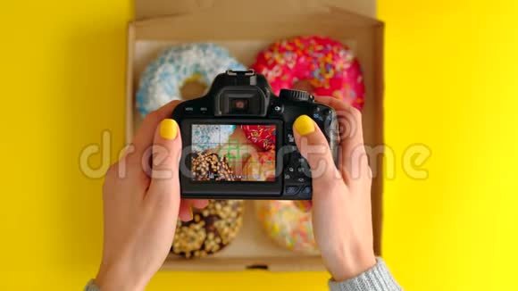 女人手拿着盒里美味甜甜圈的照片相机拍照视频的预览图