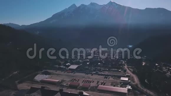 鸟瞰位于山谷中的小镇周围是被树木覆盖的高山剪辑在空中飞行视频的预览图