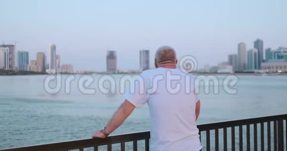 老人看着海湾站在海滨的后景看着美丽的景色视频的预览图