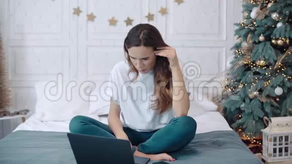在新年装饰的房子里集中的女性坐在沙发上拿着笔记本视频的预览图
