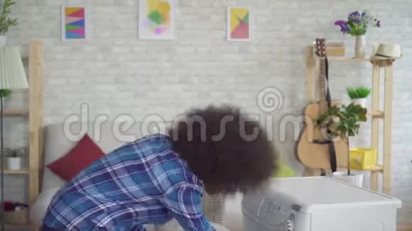 美国黑人家庭主妇穿着衬衫做家庭作业在家里洗衣服视频的预览图