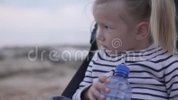 小女孩坐在婴儿车里喝着瓶子里的水视频的预览图