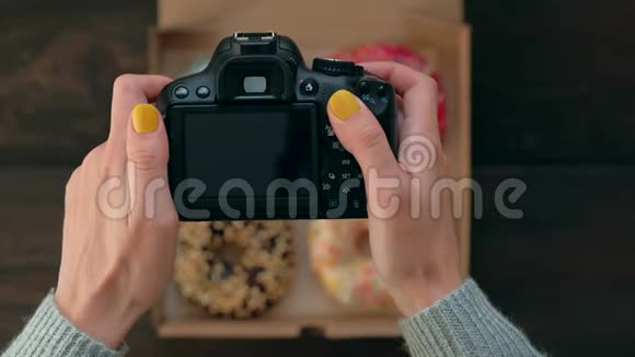 女人手拿着盒里美味甜甜圈的照片相机拍照视频的预览图