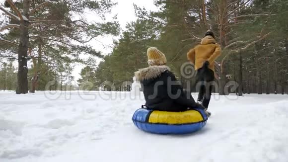 男人在冬季公园的雪地上滚动女人后景视频的预览图