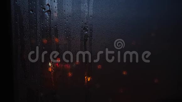 晚上雨滴落在玻璃上的特写和透过窗户模糊的光点概念视频的预览图